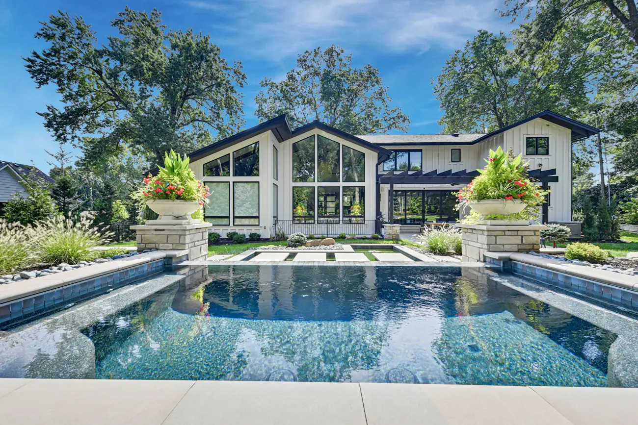 Pool reflecting a modern home with tall windows