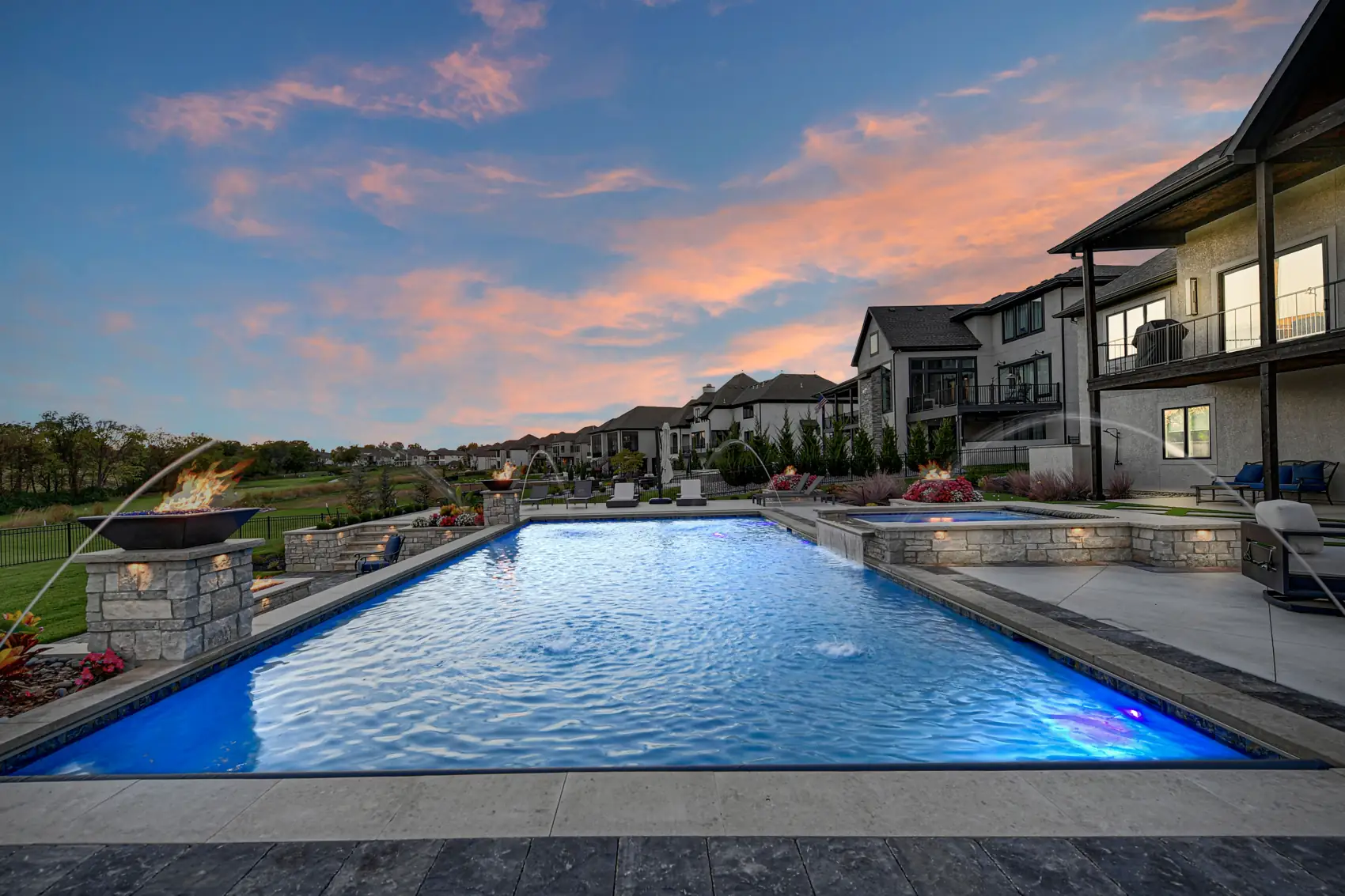 Pool with fire bowls and deck jets at sunset